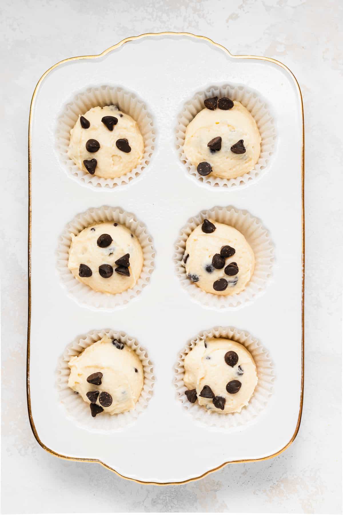 chocolate chip ricotta muffins in a muffin tin ready to be baked.