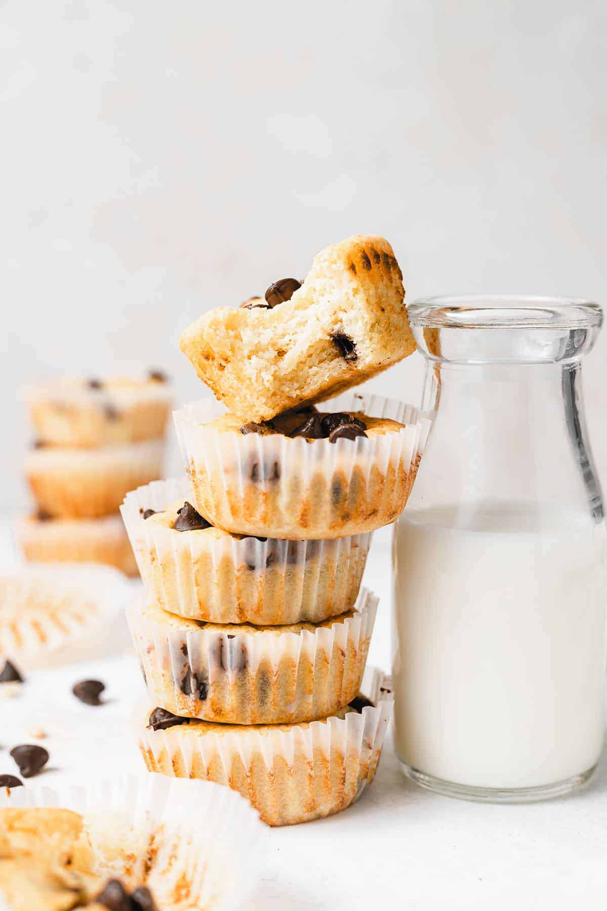 chocolate chip ricotta muffins in muffin liners next to a glass of milk.