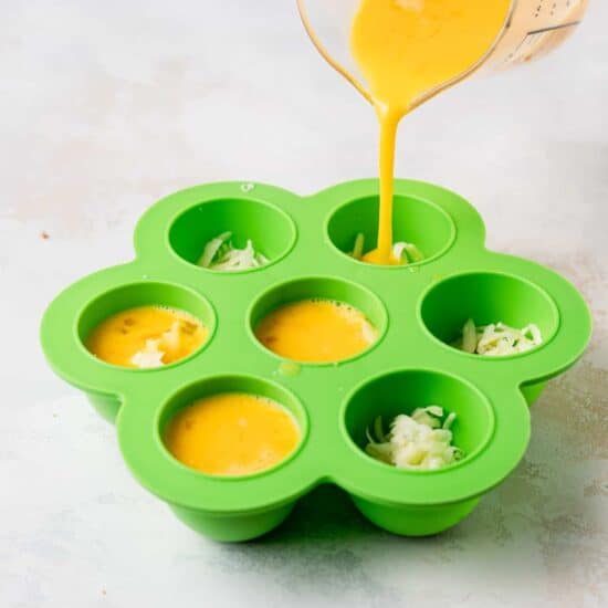 Instant pot cheesy egg bites being poured into a green muffin tin.