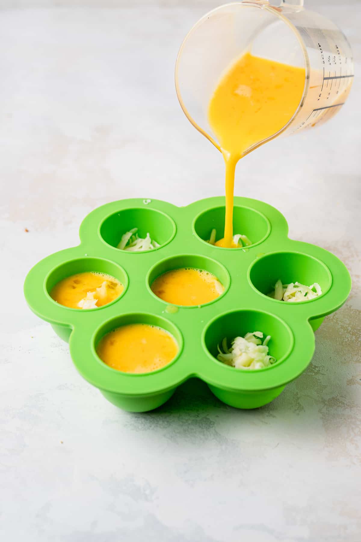 Egg mixture being poured in silicone molds for instant pot cheesy egg bites.