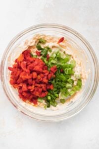 a bowl filled with red peppers and green onions.