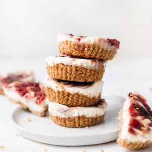 a stack of strawberry cheesecakes on a white plate.