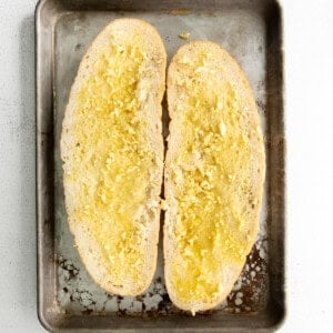 Sliced Italian loaf with butter and garlic spread on both sides.