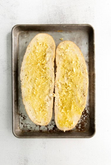 Sliced Italian loaf with butter and garlic spread on both sides.