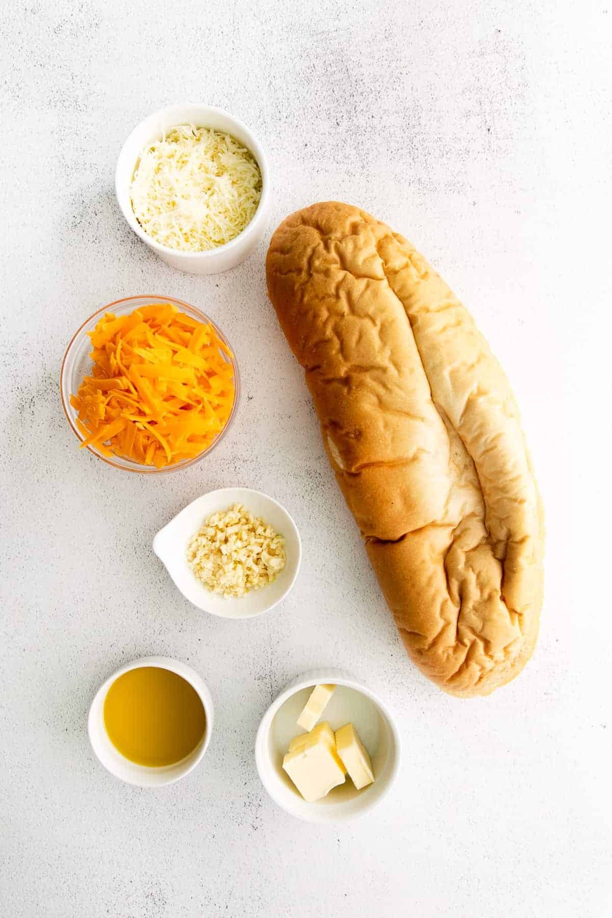 All the ingredients for cheesy garlic bread on the counter. 