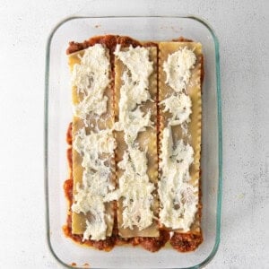 lasagna in a glass baking dish with cheese on top.