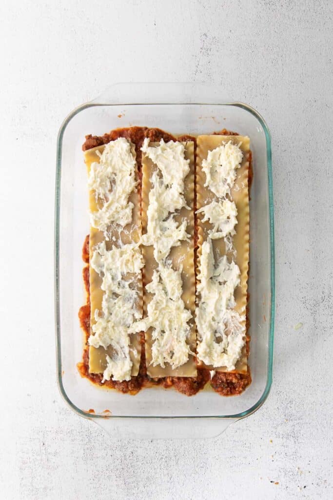 Lasagna noodles with ricotta cheese spread over the top. 