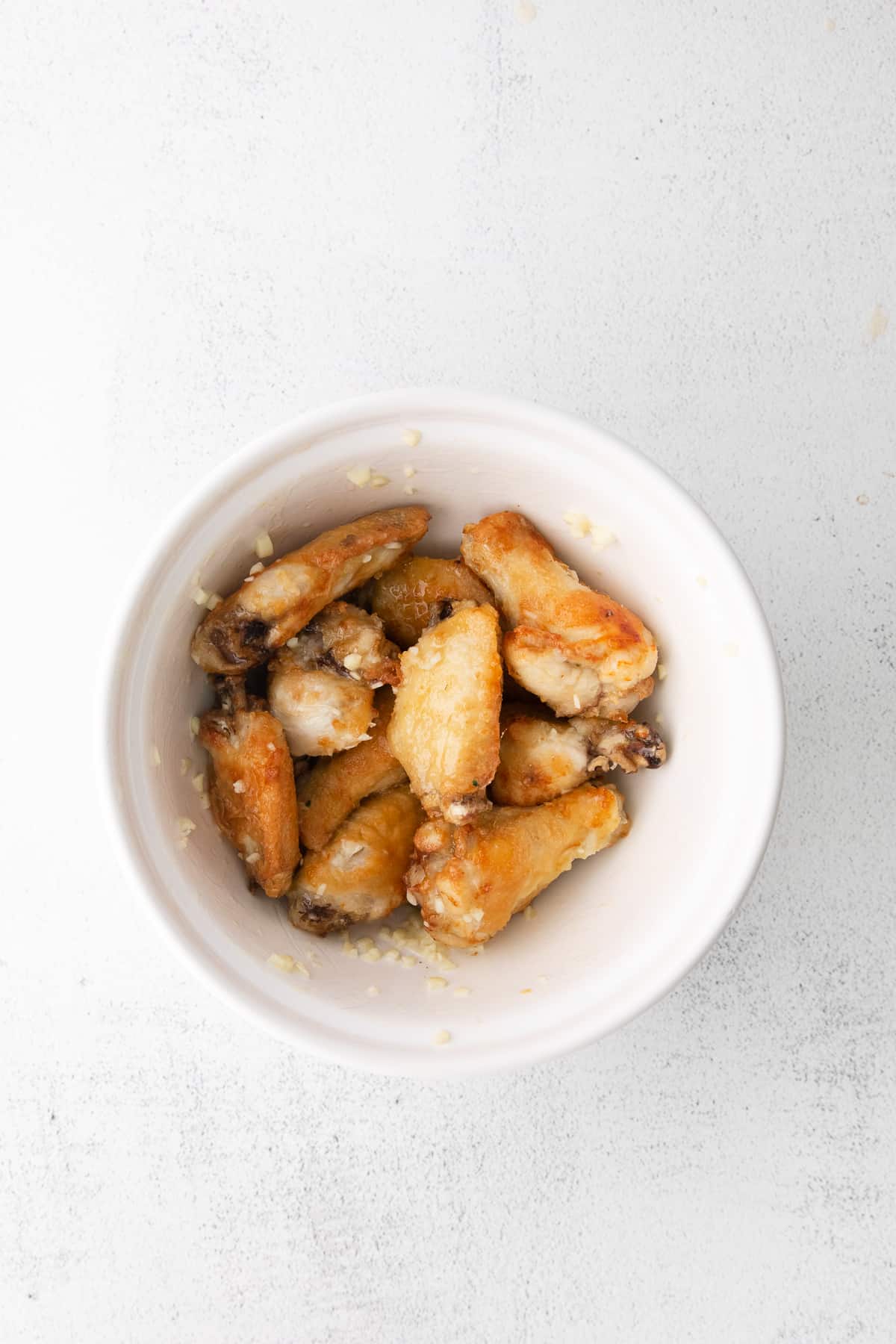 air fryer wings tossed in garlic parmesan sauce in a bowl