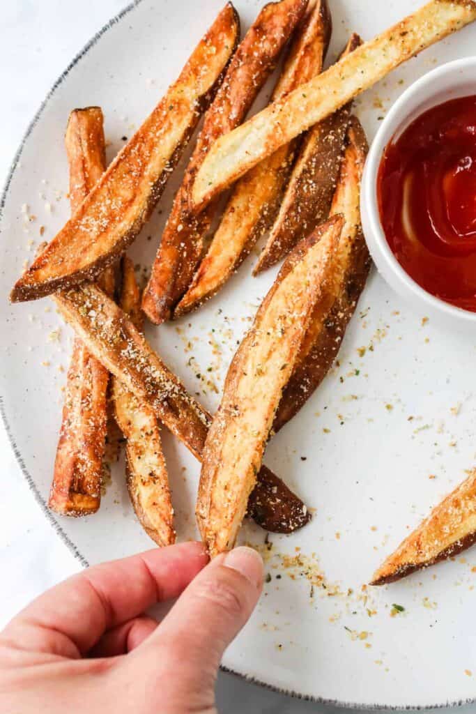 hand holding fries on plate