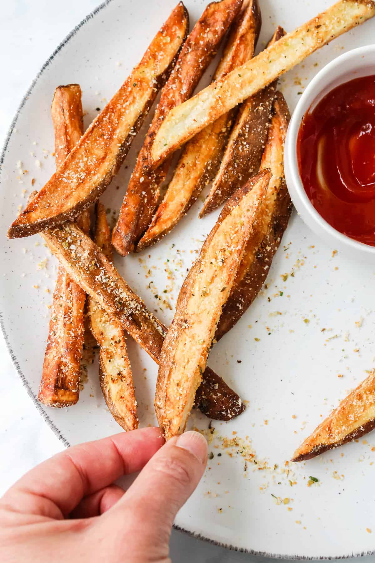 hand holding fries on plate