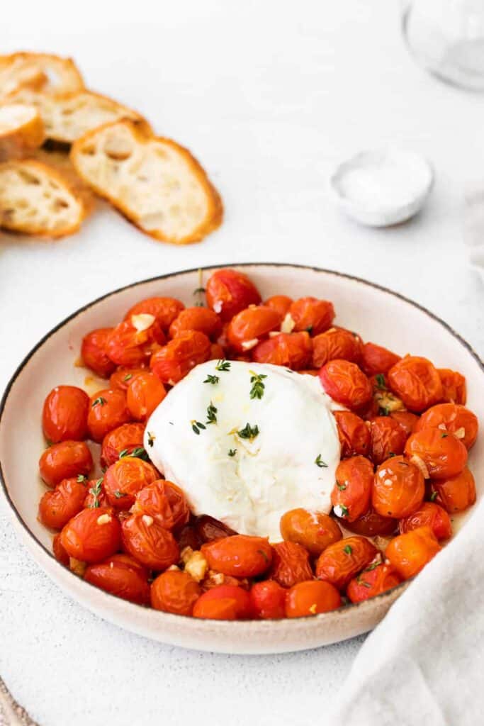 warm burrata and roasted tomatoes in a bowl and sprinkled with fresh thyme