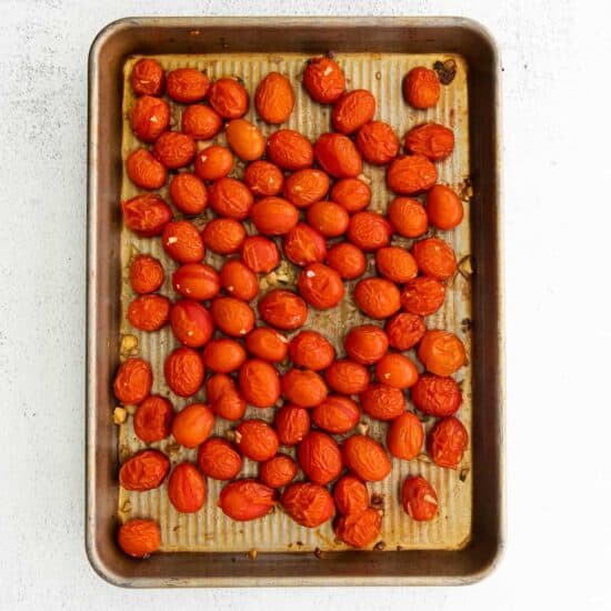 Apricots roasted on a baking sheet served with warm burrata and roasted tomatoes.