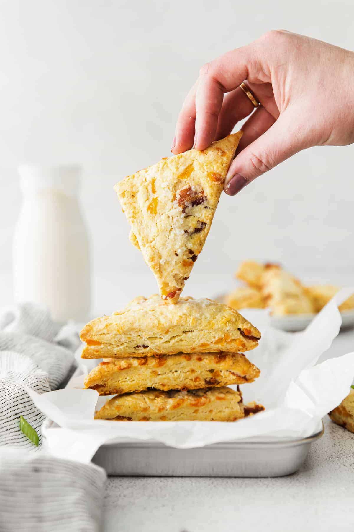 A hand holding a bacon and cheddar scone. 