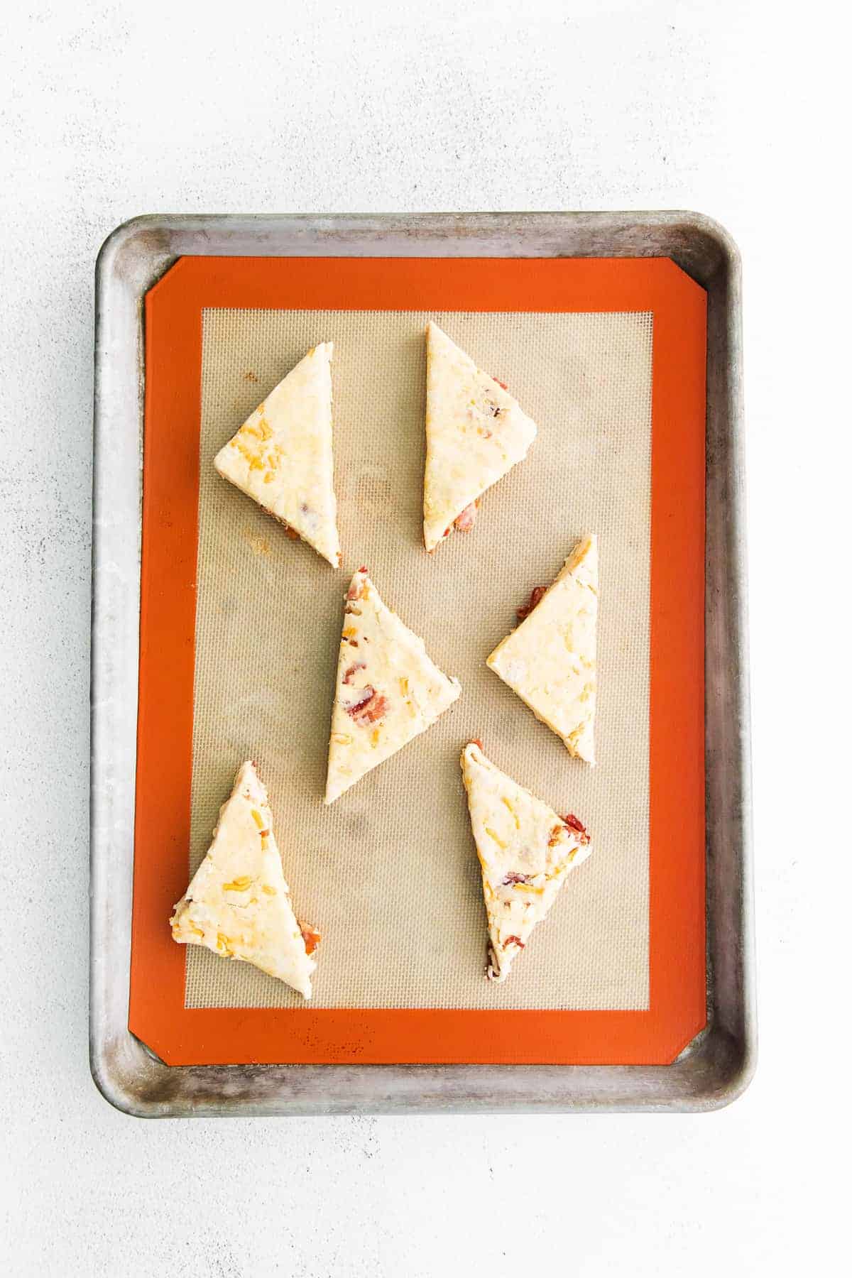 Bacon and cheddar scones on a baking sheet. 