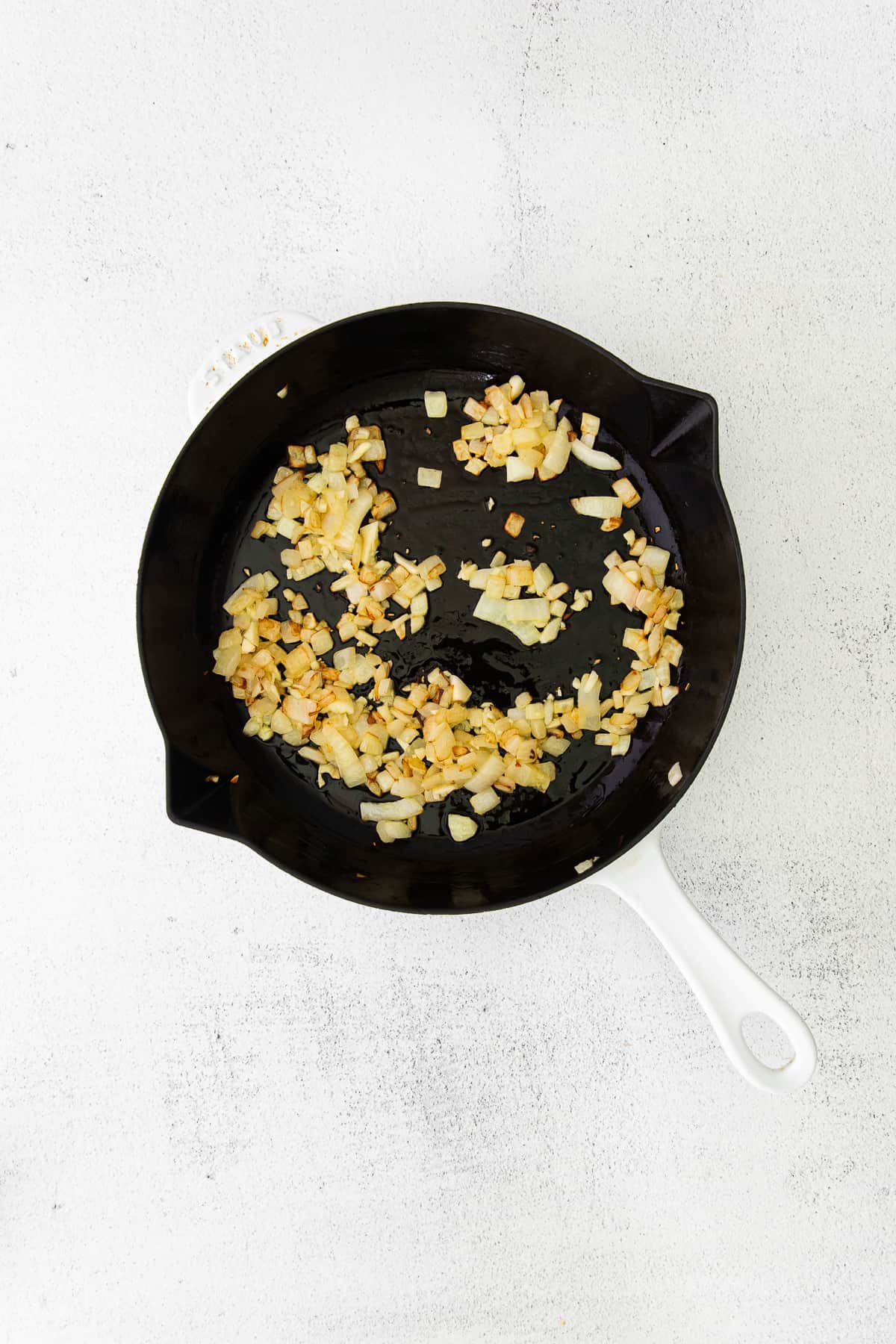 onions and garlic being sautéed in a cast iron skillet