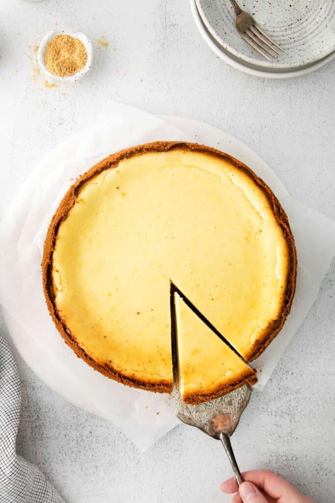 Baked cheesecake with a piece being cut from it. 