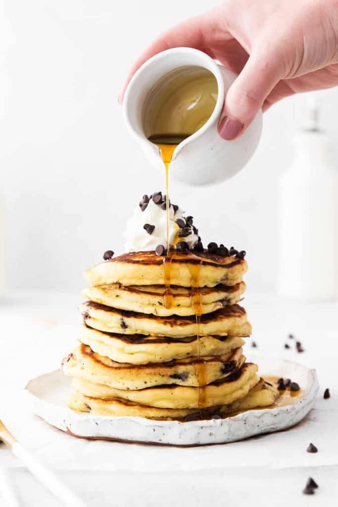 pouring maple syrup on pancakes