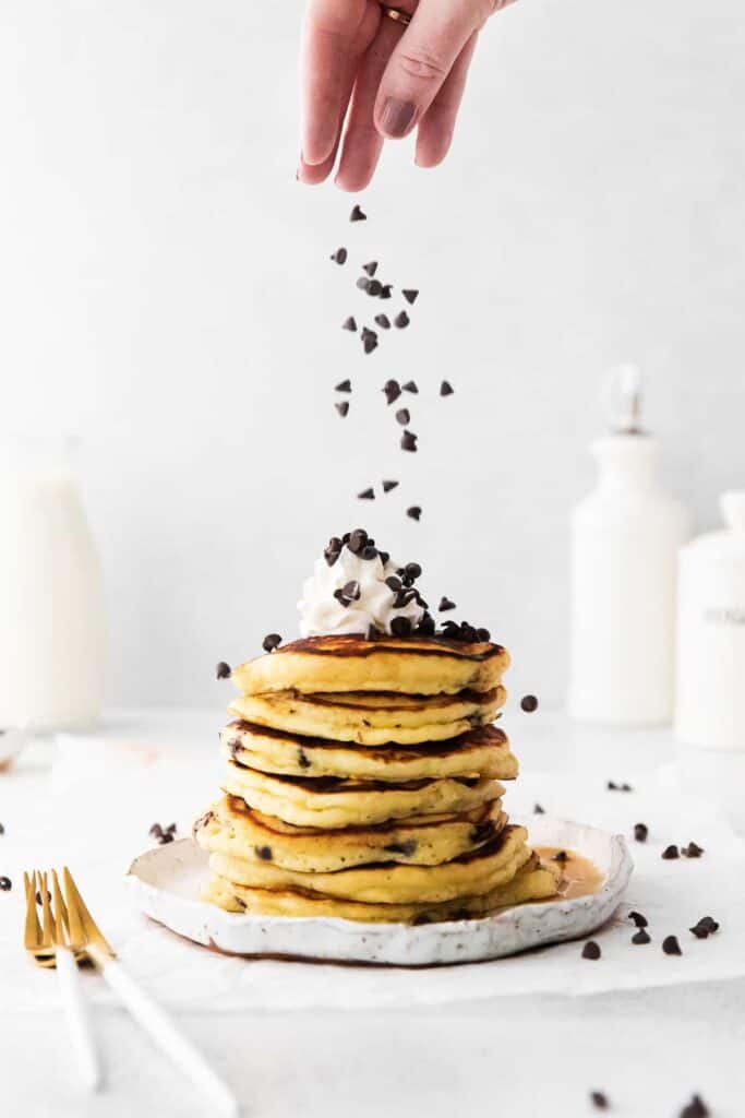 sprinkling chocolate chips on pancakes