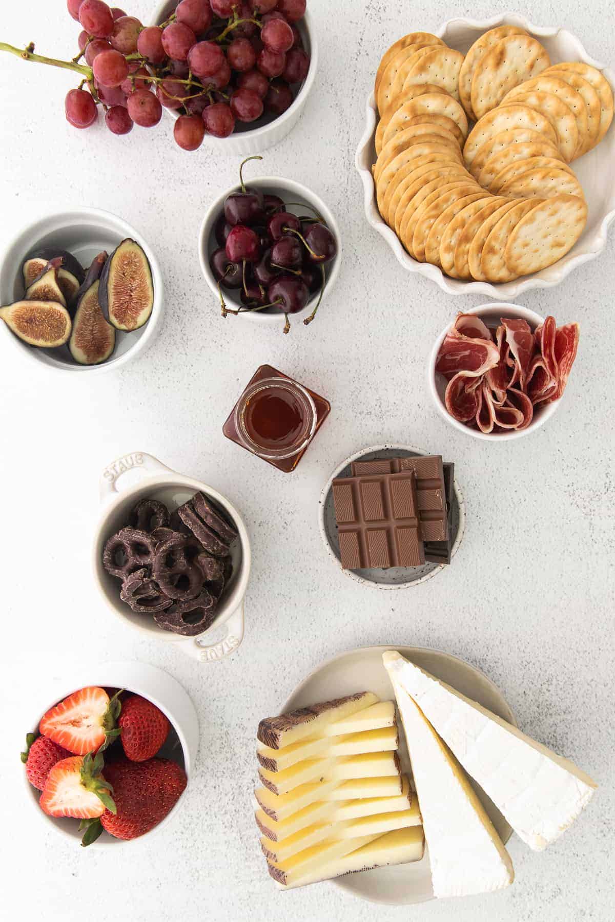 ingredients for a chocolate and cheese board in small bowls ready to be assembled