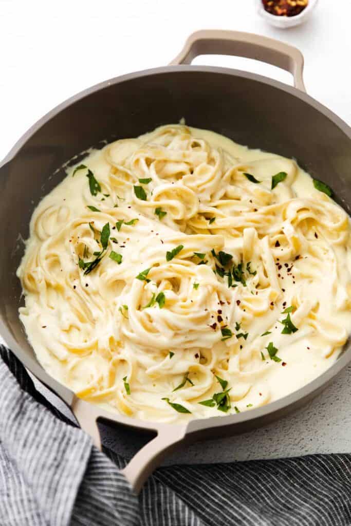 alfredo sauce with cream cheese tossed with fettuccine noodles and topped with parsley