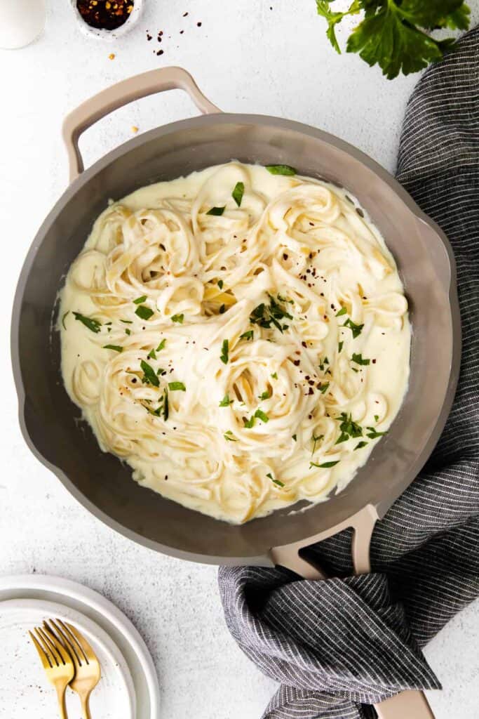 alfredo sauce with fettuccine noodles in a skillet.