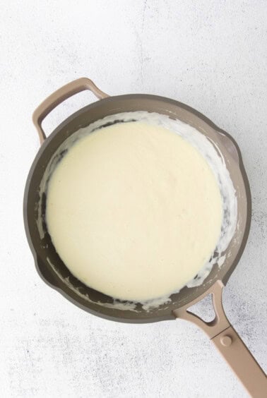 a frying pan with alfredo sauce and cream cheese.