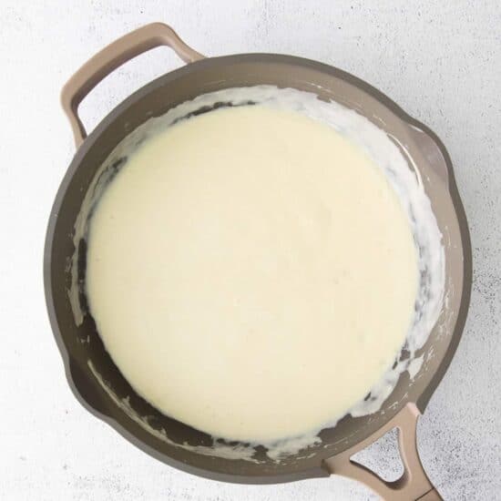 a frying pan with alfredo sauce and cream cheese.