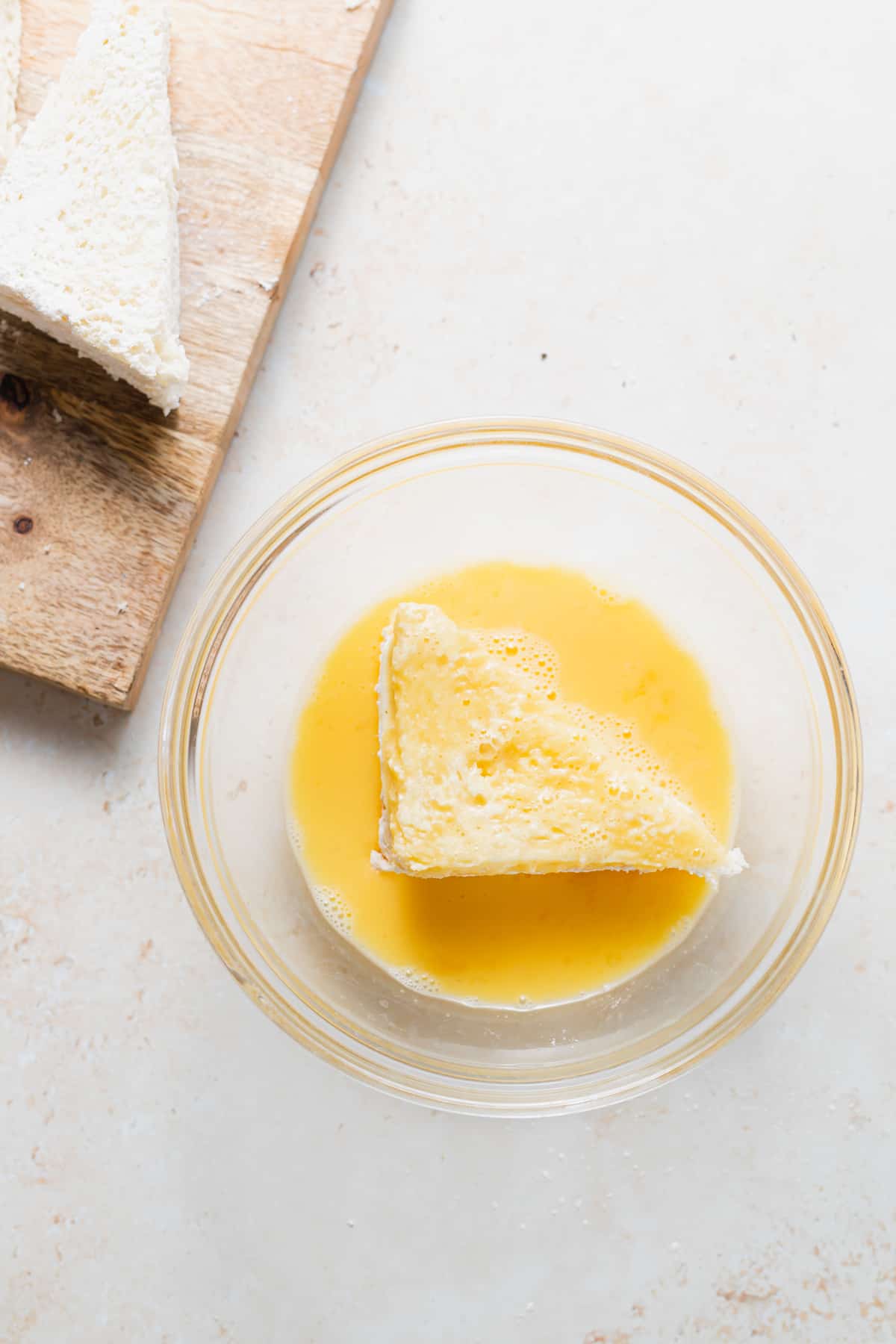 slice of mozzarella in carrozza dredged in a bowl of eggs