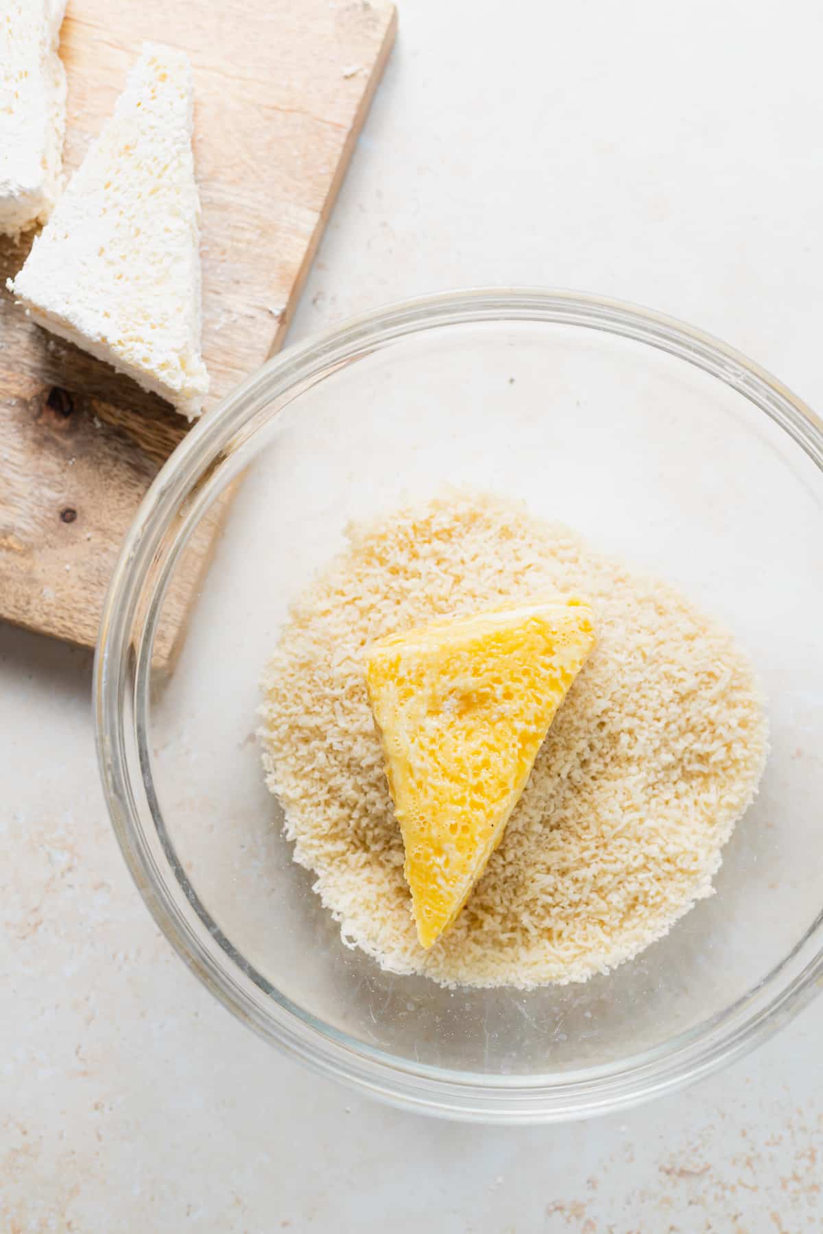 mozzarella in carrozza sandwich in a bowl being dredged through breadcrumbs