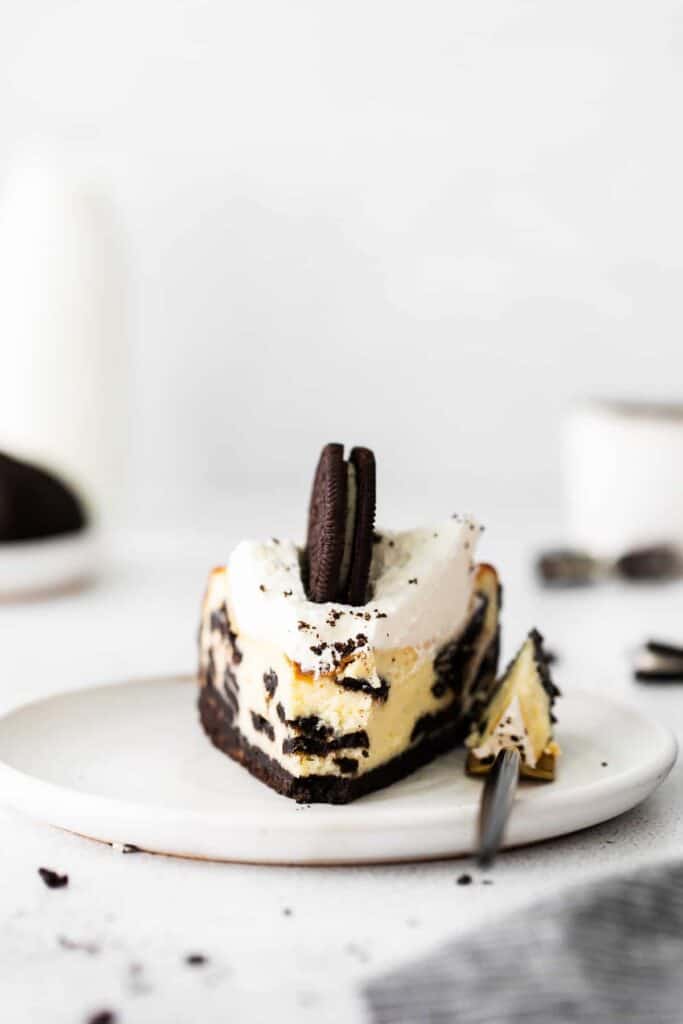 slice of oreo cheesecake on a plate with a bite on a fork