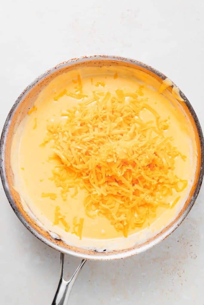 shredded cheese melting in a skillet for pretzel cheese dip