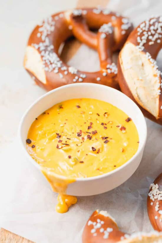 A bowl of cheesy pretzel dip served with pretzels.