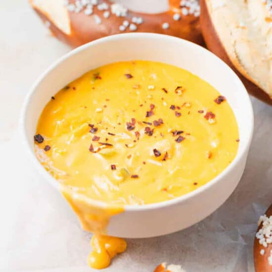 A bowl of soup with pretzels, pretzel buns, and pretzel cheese dip.