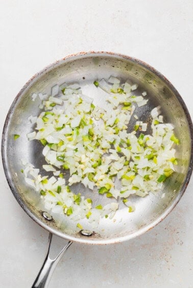 A frying pan with onions sautéing in pretzel cheese dip.