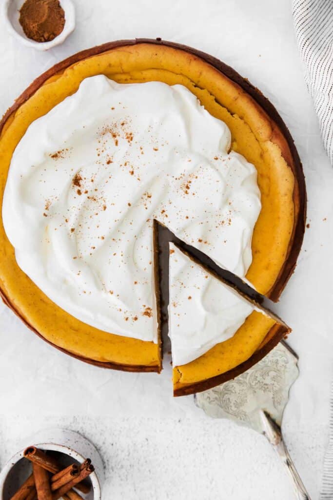 pumpkin chai cheesecake topped with whipped cream and a dash of chai spice