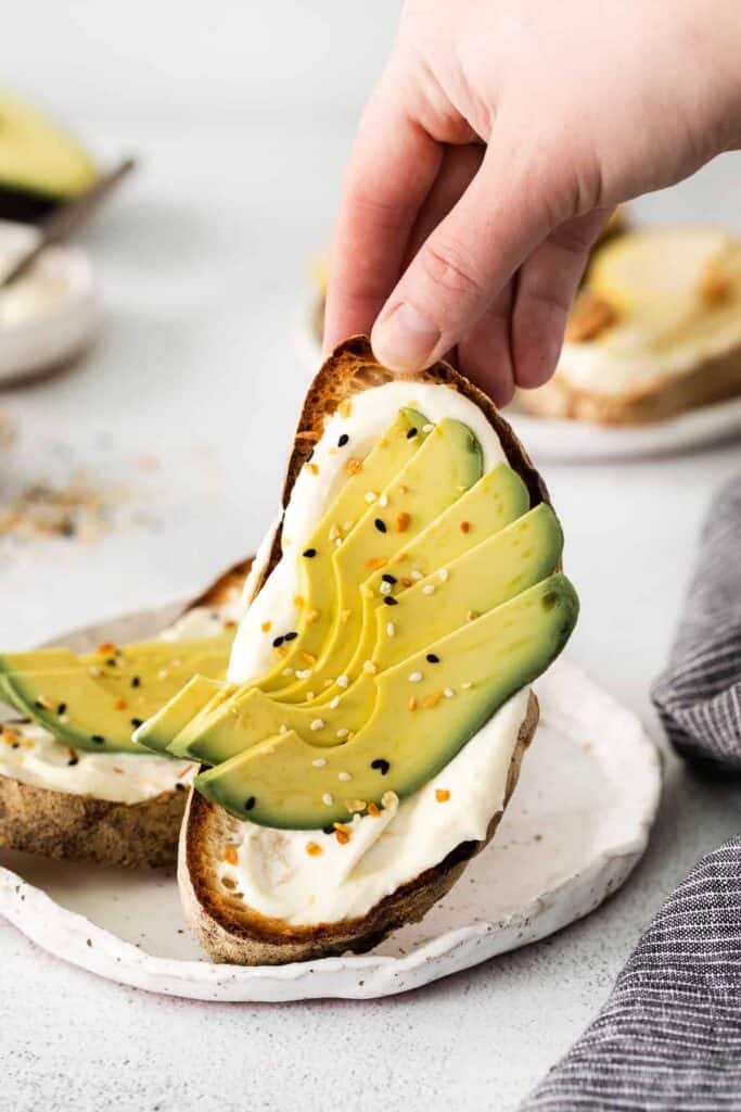 A piece of ricotta toast with avocado and everything bagel seasoning. 