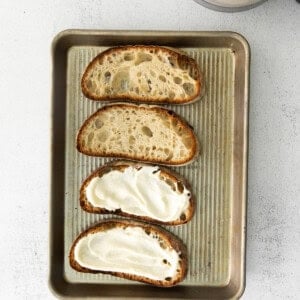 Four slices of bread with ricotta toast on a baking sheet.