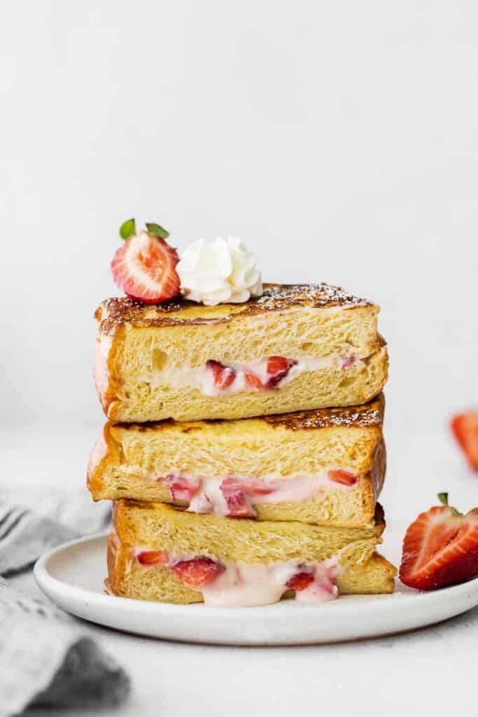Strawberries and cream stuffed french toast stacked three slices high.