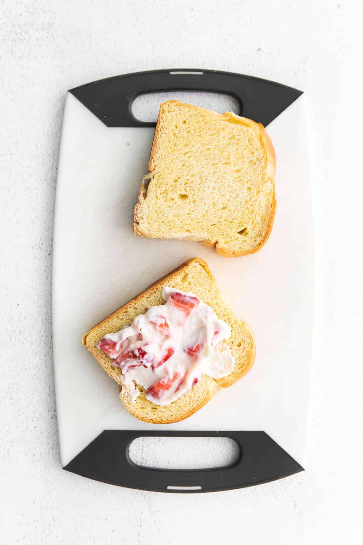 Two pieces of brioche bread with a strawberry cream cheese mixture ready to be made into stuffed french toast.