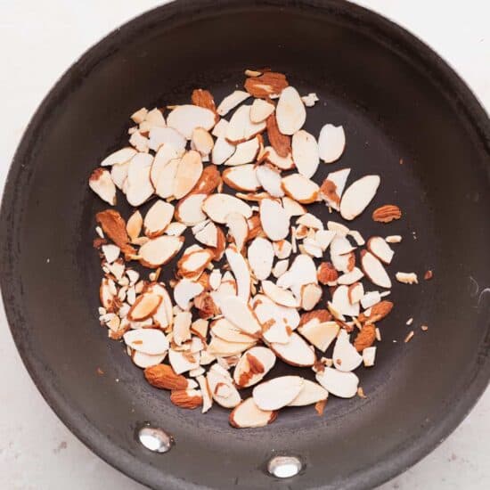 A frying pan with almonds used in an arugula goat cheese salad.