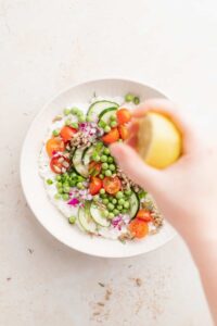 A person adding lemon juice to a cottage cheese salad.