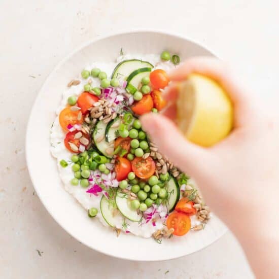 A person adding lemon juice to a cottage cheese salad.