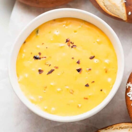 a bowl of cheesy dip with pretzels and pretzel sticks.