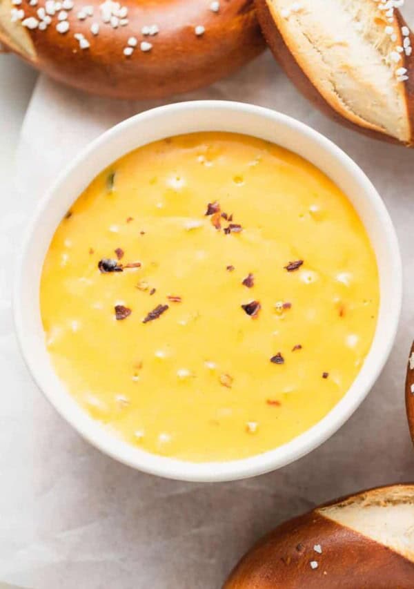 a bowl of cheesy dip with pretzels and pretzel sticks.