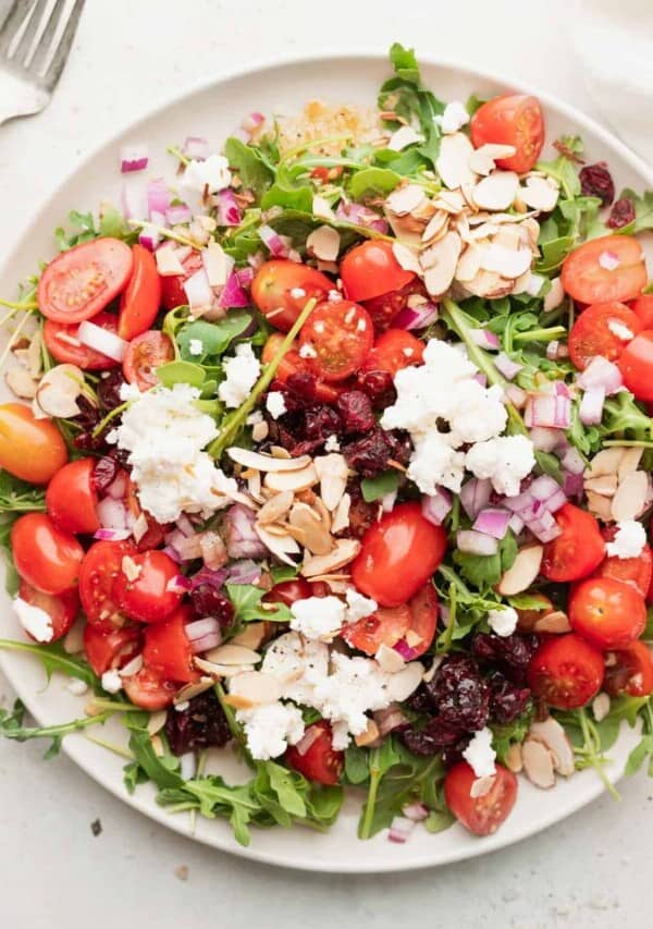 a plate of cranberry arugula salad with feta and almonds.