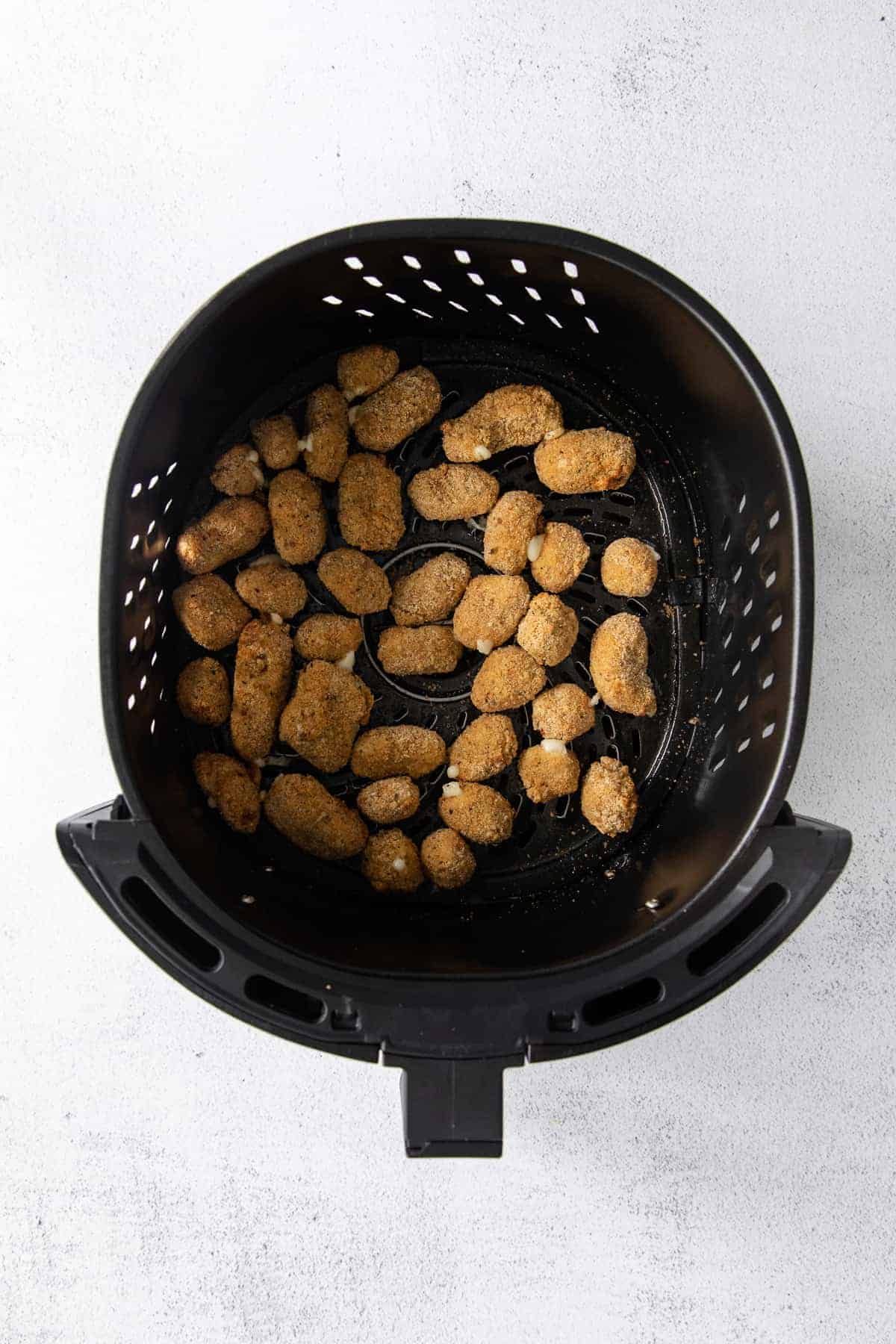 cheese curds in an air fryer basket after being air fried