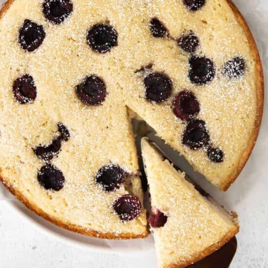 A slice of blueberry cherry cake on a white plate.