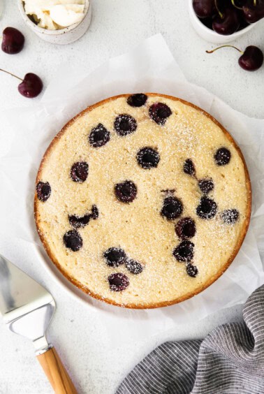 A cherry ricotta cake served on a plate with a knife nearby.