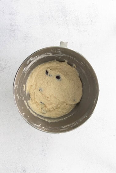 a bowl of dough with blueberries and cherries in it.
