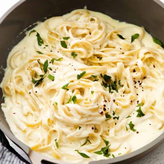 cheesy pasta with alfredo sauce and parmesan cheese cooked in a pan.